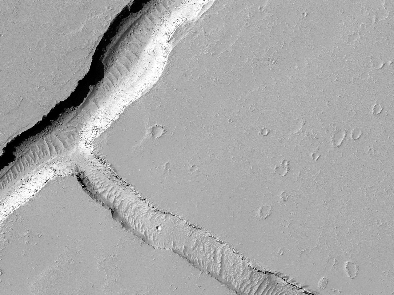 Spricka på slätterna sydöst om Ascraues Mons och norr om Noctis Fossae