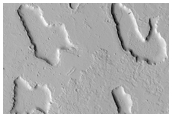 Windows in a Mantling Deposit Open Onto a Platy-Ridged Substrate 