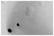 Dark Rimless Pits in Tharsis