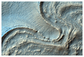 Gullies and Curved Ridges at the Base of Crater Walls