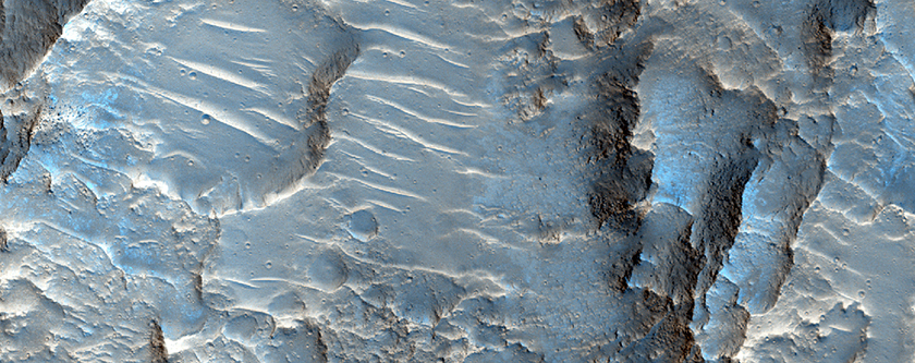 Impact Crater Exposing Bedrock West of Ganges Chasma