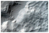 Crater-Related Pitted Materials in 8-Kilometer Diameter Hellas Region Crater