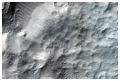 Crater-Related Pitted Materials in 8-Kilometer Diameter Hellas Region Crater
