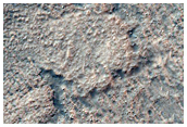Ejecta and Possible Bedrock on Crater Floor in Aonia Terra
