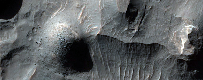Büyük bir kraterin tabanındaki aşınmış katmanlı rüsubatlar