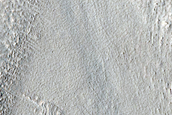 Layered Terrain Emerging from under Mantling Deposits